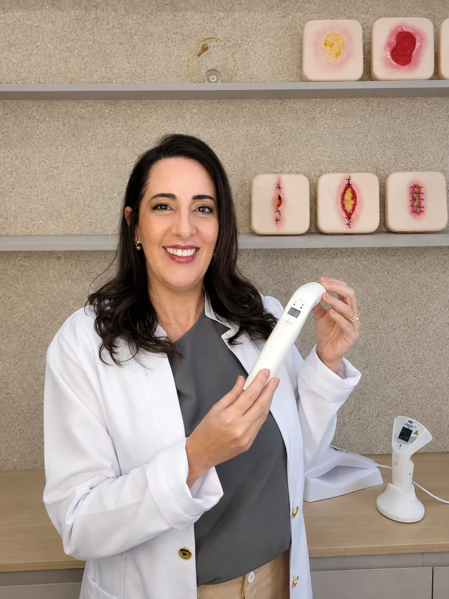 Taisa Mazuchi no consultório, com o aparelho de laser e os modelos de feridas